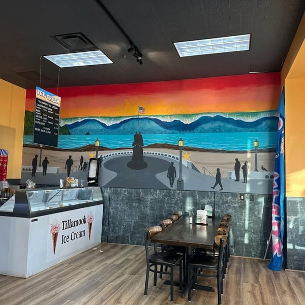 Tillamook Ice Cream shop interior with a vibrant mural of a coastal scene and a long dining table.